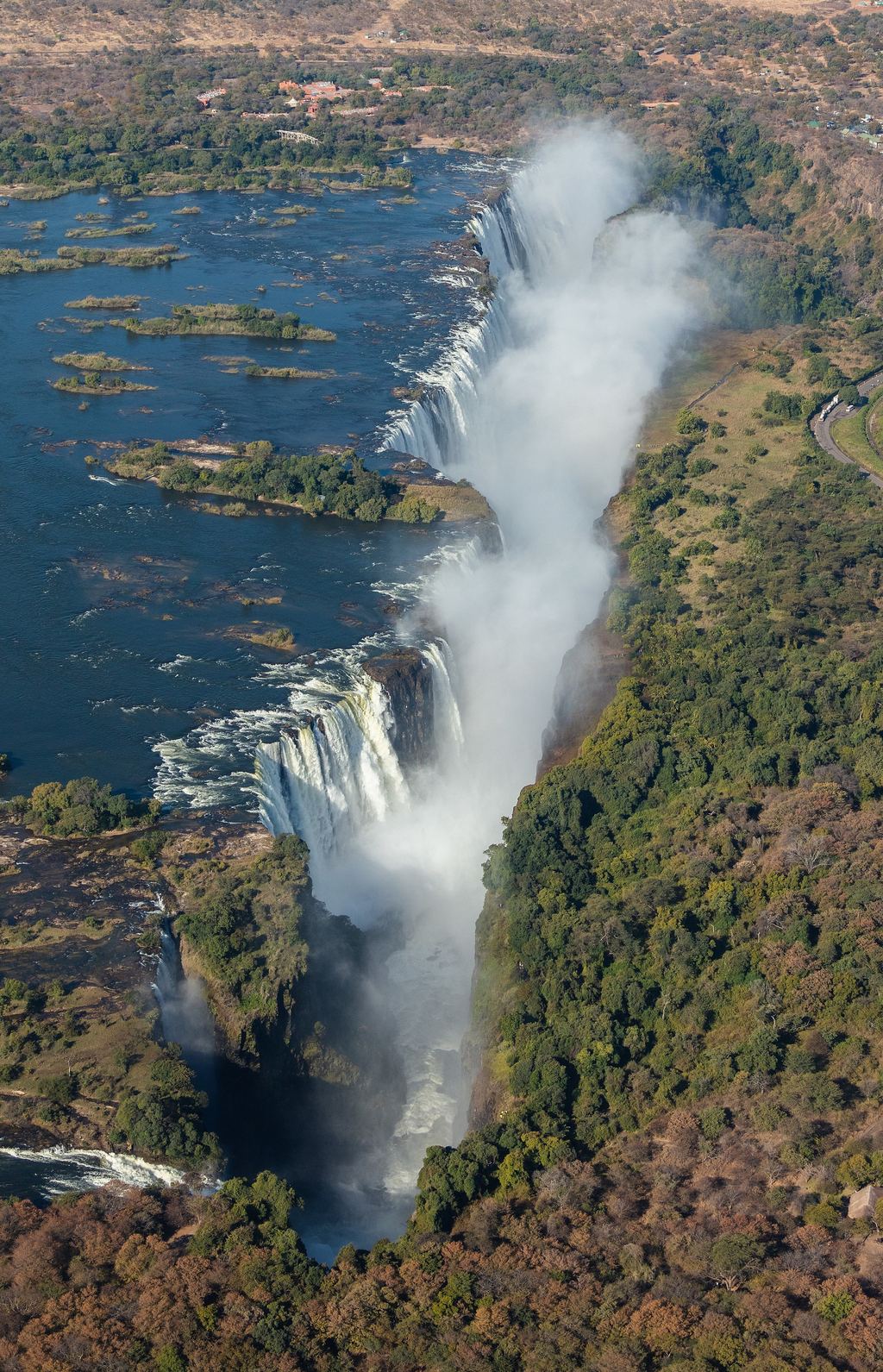 The curtain of water at Victoria Falls plunging into the Batoka Gorge, framed by riverine forest